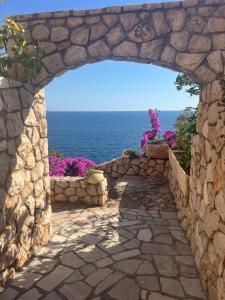 an archway in a stone wall with a view of the ocean at Modern Seaview Apartment with a Pool in Dobra Voda