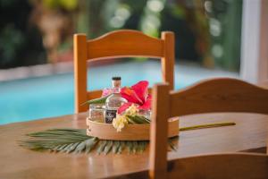 a bottle of potion and flowers on a table at Evasion tropicale villa 6 personnes avec piscine in Saint-Louis
