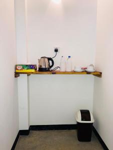 une pièce avec une étagère sur un mur avec une bouilloire et une poubelle dans l'établissement Wild Safari River Cottage udawalawe, à Uda Walawe 5 autres photos