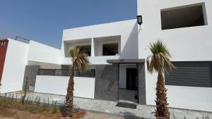 a white house with two palm trees in front of it at Beachside Bliss: Cozy Surf Villa in Mirleft