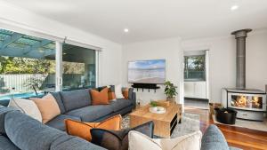 Una sala de estar con un sofá y una chimenea. en Azure House, en Callala Beach