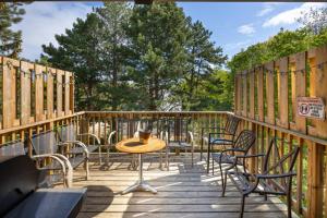 eine Holzterrasse mit Stühlen, einem Tisch und Stühlen in der Unterkunft Margaritaville - Big Space with Lots of fun and Hot Tub 38R in Blue Mountains
