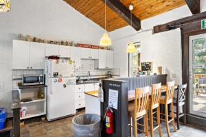 eine Küche mit weißen Geräten sowie einem Tisch und Stühlen in der Unterkunft Margaritaville - Big Space with Lots of fun and Hot Tub 38R in Blue Mountains