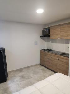 cocina con paredes blancas y armarios de madera en Xliving Host and Rooms, en Bogotá
