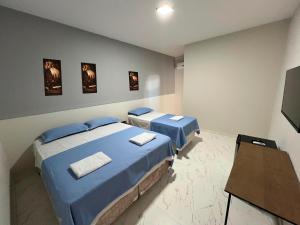 two beds in a room with blue sheets at Hotel Acqua Park in Capim Grosso