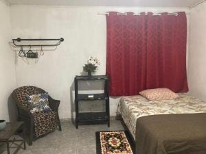 a bedroom with a red curtain and a bed and a chair at Casa em Parnamirim próximo ao centro in Parnamirim