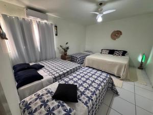Cette chambre comprend 3 lits avec des draps bleus et blancs. dans l'établissement Pousada Caminho do Mar, à Santa Cruz Cabrália 20 autres photos