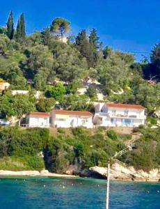 a house on top of a hill next to the water at Aronis Spyros Panoramic Seaview Apartments in Longós