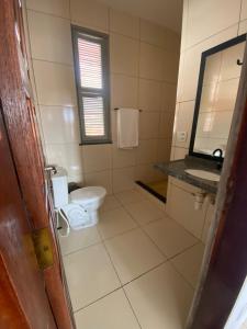 ein Badezimmer mit Toilette, Waschbecken und Spiegel in der Unterkunft Pousada Marazul in Caucaia
