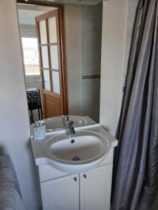 a bathroom with a sink and a shower curtain at Voiles et Terrasses by Corinne Résidence face au port in Le Tréport