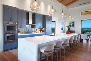 a kitchen with blue cabinets and a large island with bar chairs at Ke Kai Nui at Kukuiula in Koloa