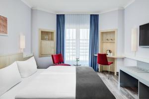 um quarto de hotel com uma cama e duas cadeiras vermelhas em IntercityHotel Hamburg Altona em Hamburgo