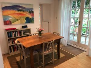 ein Esstisch mit Stühlen und einer Vase mit Blumen in der Unterkunft Garden Cottage in Twickenham