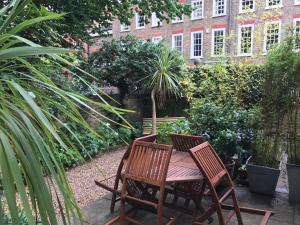 2 Holzstühle und ein Tisch im Garten in der Unterkunft Garden Cottage in Twickenham