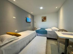 two beds in a room with a tv on the wall at Maraki Suítes Maragogi 150M do Mar in Maragogi +28 photos