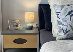 a bed with a table with a lamp on a night stand at Wielki Błękit Apartament z salonem i dwiema sypialniami in Giżycko