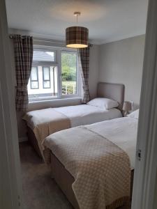 a bedroom with two beds and a window at Pullman Lodge in Glemsford +3 photos