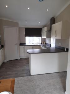 a kitchen with white cabinets and a white counter top at Pullman Lodge in Glemsford