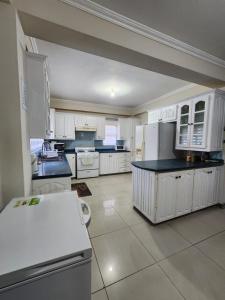 una gran cocina con armarios blancos y encimeras negras en Palm Springs Apartments, en Couva