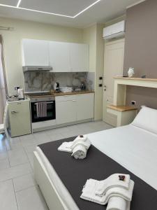 a white kitchen with white cabinets and towels on a bed at Perla Marina B&B in Nicotera Marina