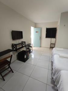 a room with two beds and a flat screen tv at Bendita Parada - Pousada in Sobral
