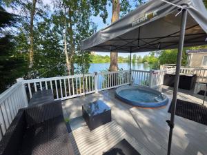 a hot tub on a deck with an umbrella at Nestled beneath the trees is this beauty a 3 bed property with hot tub and stunning views in Tattershall