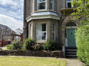 a house with a green door and a stone wall at The Furness Haven in Barrow in Furness