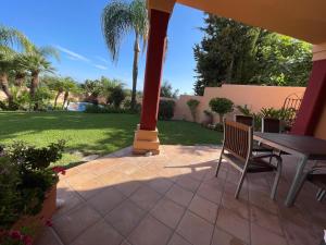 eine Terrasse mit einem Tisch, Stühlen und einer Liegewiese in der Unterkunft Chalet pareado in Marbella