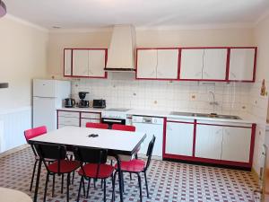 a kitchen with a white table and red chairs at La maison du Vigneron in Veuzain-sur-Loire