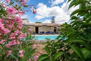 a villa with a swimming pool and pink flowers at Château Clos des Maurins in Vérac