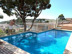 a man standing next to a swimming pool at Appartement spacieux, vue imprenable in Roquebrune-Cap-Martin