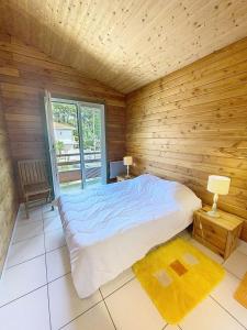 a bedroom with a large bed in a wooden room at Résidence 03134-lacanau Ocean - Chalet bois indépendant, 3 chambres, 6 personnes proche plage Lacanau océan MAE-0531 in Lacanau