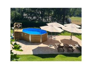 a pool with two umbrellas and two chairs at Landhaus Weickenhof Comfortable holiday residence in Oberweickenhof
