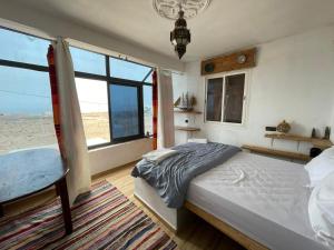 a bedroom with a bed and a large window at EL Faro Surfstay in Tamri +10 photos