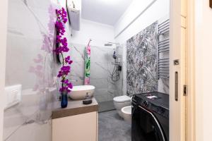 a bathroom with a toilet and a sink with purple flowers at Casa Bella Binario 11 Ciampino in Ciampino +15 photos