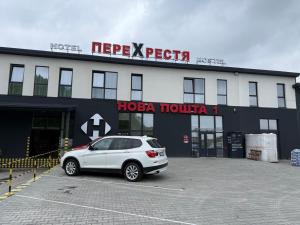 a white car parked in a parking lot in front of a building at Hotel Hostel Перехрестя in Chistilov