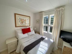 1 dormitorio con cama con almohada roja y ventana en Luxury Garden Retreat 2B Sandton, en Sandton 95 fotos más