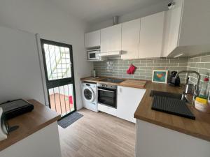 a kitchen with white cabinets and a washer and dryer at Casa Álamo en Chipiona in Chipiona