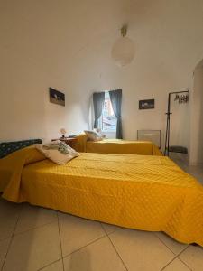 two beds in a room with yellow sheets at La casetta della nonna in Camagna Monferrato
