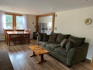 un salon avec un canapé vert et une table dans l'établissement Green River Cottage, à Guilford