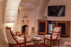a living room with two chairs and a fireplace at Lagoon Cave Suites in Urgup