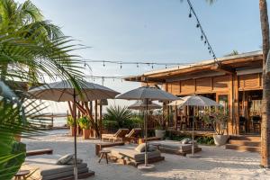 a patio with umbrellas and lounge chairs and tables at Hotel Siesta Holbox in Holbox Island