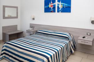 una camera con un letto con una coperta a righe di Holiday Affittacamere a Corigliano Calabro