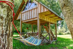 a hammock in front of a tree house at Kempingas Prie Vencavų malūno in Viencavai