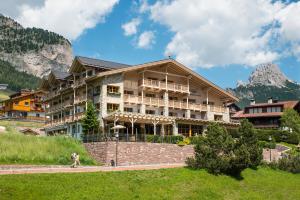 een groot gebouw in de bergen met een persoon die voor loopt bij Hotel Portillo Dolomites 1966' in Selva di Val Gardena