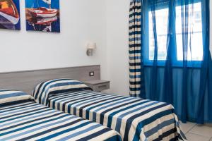 Holiday Affittacamere في كوريليانو كالابرو: سريرين في غرفة ذات ستائر زرقاء وبيضاء