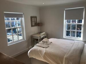 1 Schlafzimmer mit einem weißen Bett und 2 Fenstern in der Unterkunft Garden Cottage in Twickenham + 2 Fotos