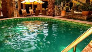 a large swimming pool with green water and an umbrella at Casona María Esther in San Miguel de Allende
