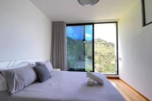 a bedroom with a large bed with a large window at Sal e Pimenta House - A Wellbeing Retreat in Machico