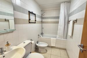 a bathroom with a toilet and a sink and a tub at Serena Bay in Câmara de Lobos